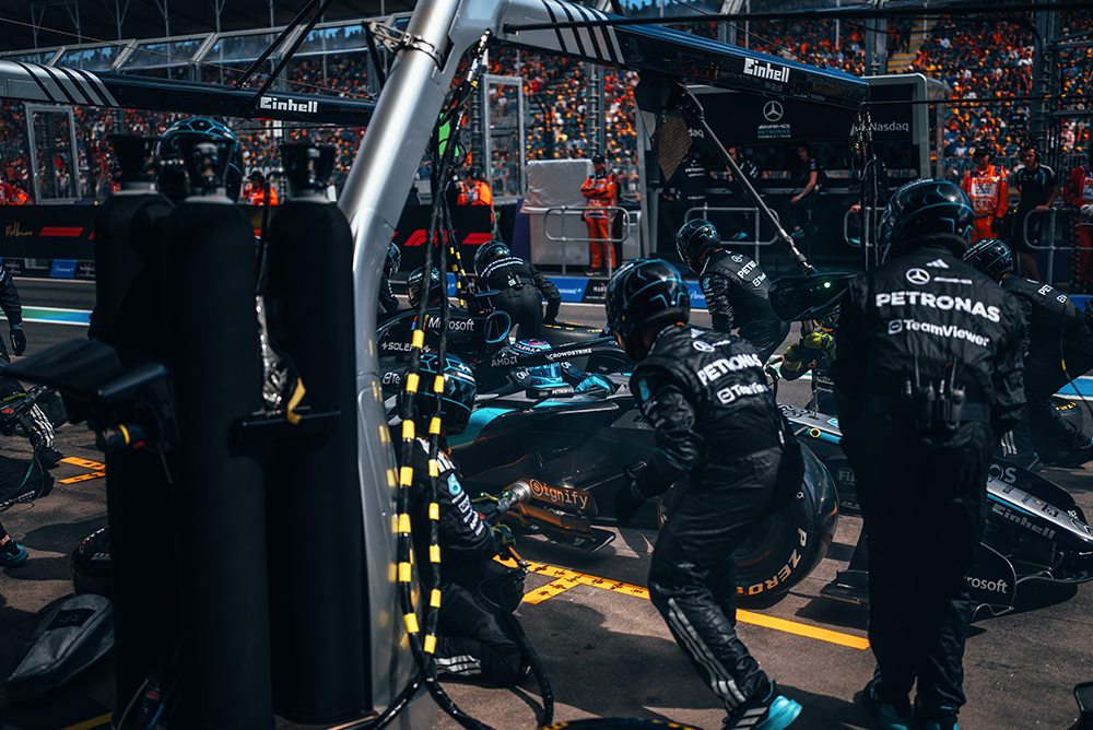 Formula 1 team working on race cars in the illuminated pit lane.